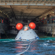 An Orion mockup being delivered to the well deck of a Navy vessel during a practice exercise held on December 2, 2022.